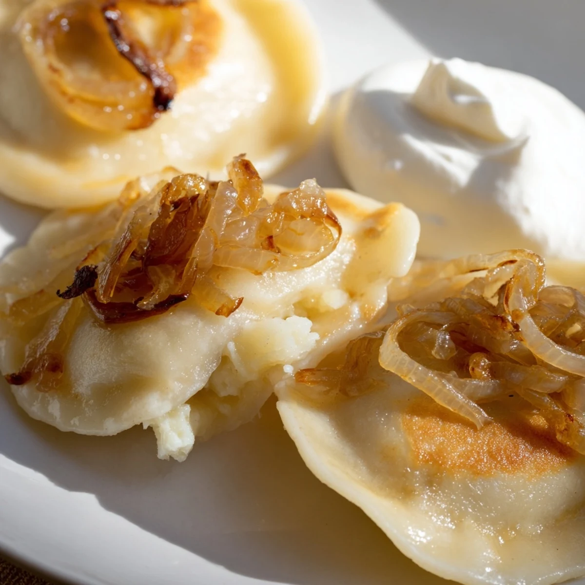 Golden-brown Polish pierogi dumplings filled with potato and cheese, served with sweet onions.