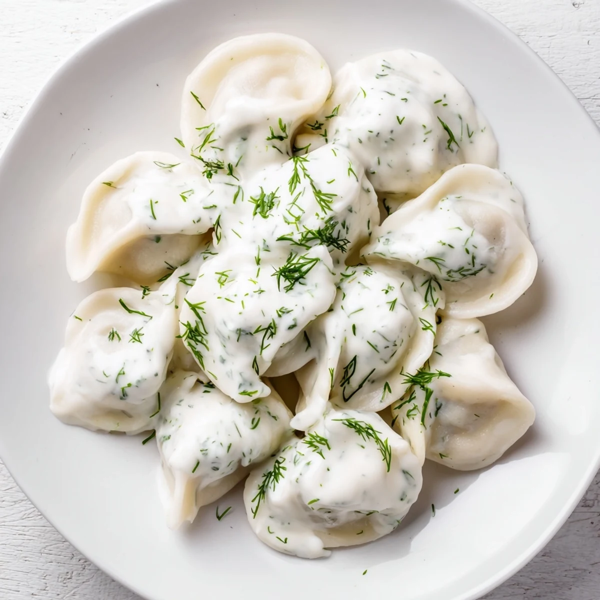Steaming hot Russian pelmeni, savory meat dumplings swimming in creamy sour cream sauce.