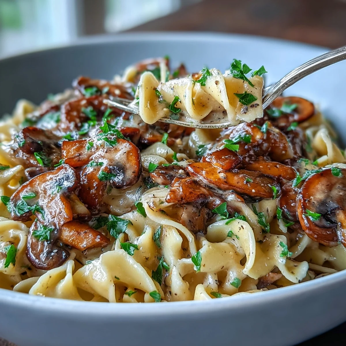 Golden fettuccine noodles are coated in a creamy, savory mushroom stroganoff sauce, garnished with fresh parsley.