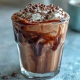 Rich and creamy chocolate cream cold brew coffee with chocolate syrup drizzle and cocoa powder garnish in chilled glasses.