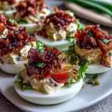 Delicious BLT Deviled Eggs: tangy, mayo-rich yolk filling paired with fresh lettuce, juicy tomatoes, and crispy bacon crumbles for bold flavor.