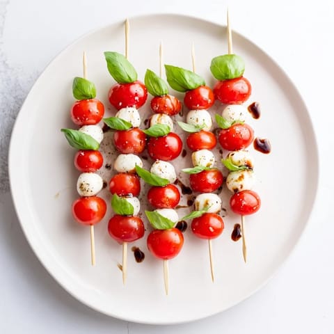 Cool, refreshing Fresh Caprese Salad Skewers—cherry tomatoes, mozzarella, and basil ready for your snacking pleasure.