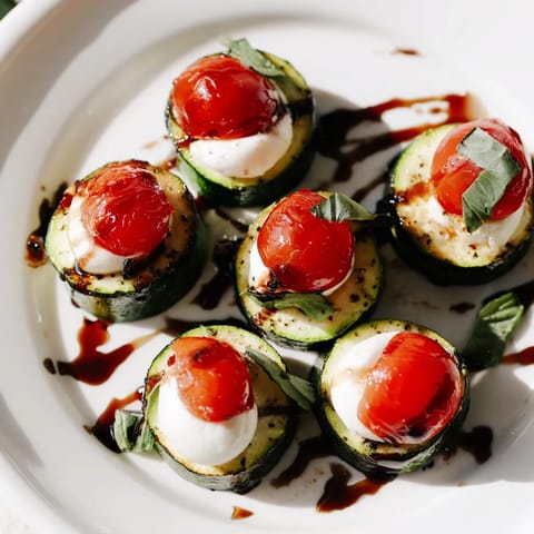Oven-baked Zucchini Caprese Bites with melted mozzarella, fragrant basil, and drizzled balsamic glaze look delicious.