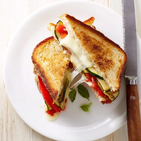 Golden-brown Roasted Veggie Caprese Grilled Cheese oozing with melted mozzarella and layered with roasted zucchini and peppers.
