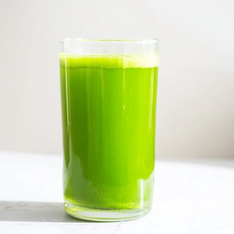 Bright green Cabbage and Kale Detox Juice in a mason jar, set against a rustic wooden table with fresh kale leaves and ginger nearby. 