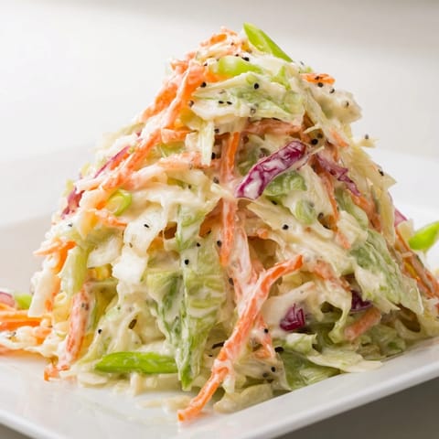 A vibrant bowl of Best Cabbage Coleslaw featuring shredded green and red cabbage with grated carrots, tossed in a creamy, tangy dressing.