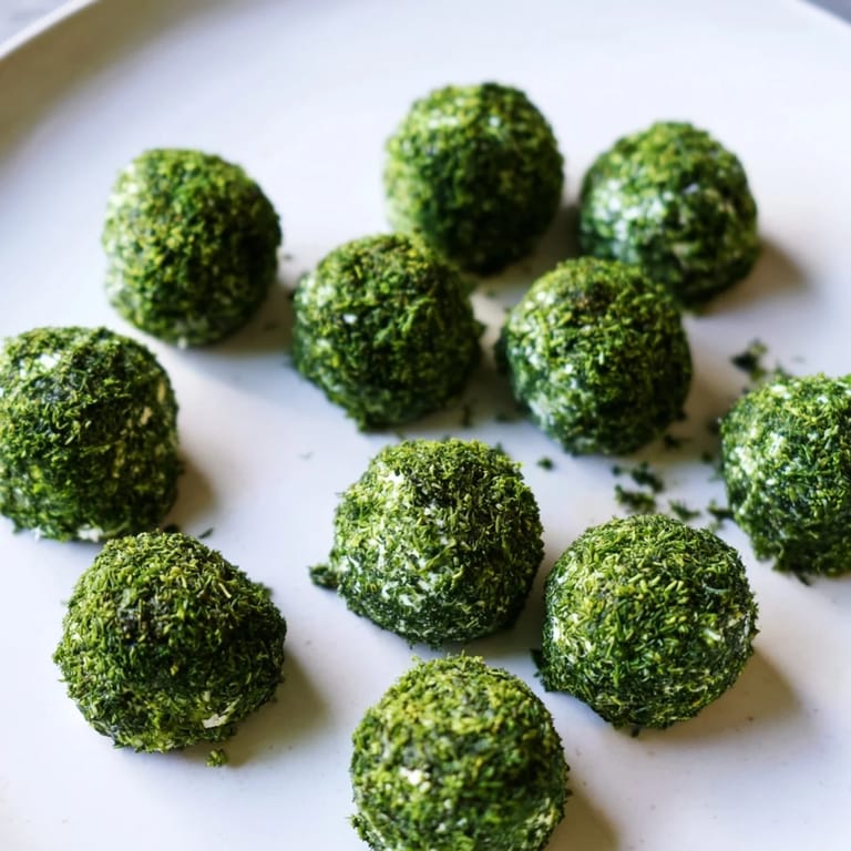 Freshly rolled "Mossy Stone" appetizers: A close-up view of goat cheese covered in green herbs.