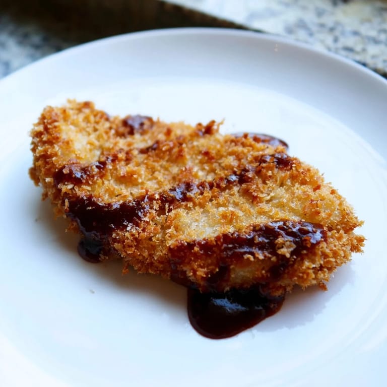 Freshly fried Chicken Katsu golden cutlet sliced to reveal juicy interior beside steamed rice.  