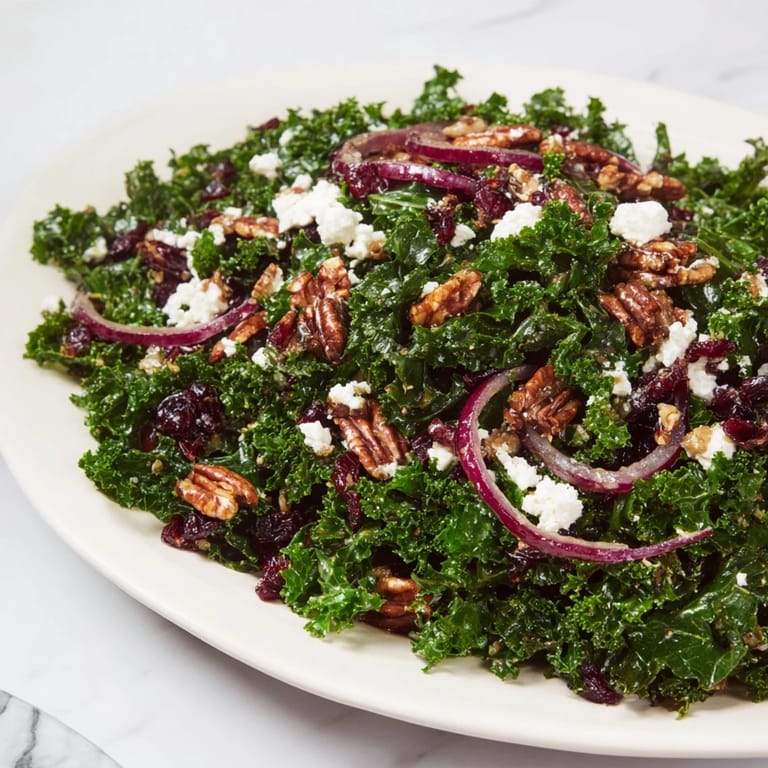 A close-up of Warm Kale Salad with Maple Mustard Dressing, showing glossy leaves, sliced red onion, and golden toasted walnuts.